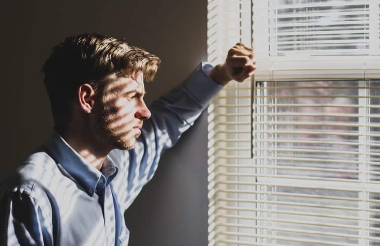 Frustrated man looking outside of a window.