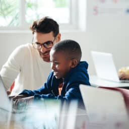 Teacher helping a young boy in computer class