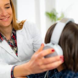 Audiologist putting headphones on a young boy