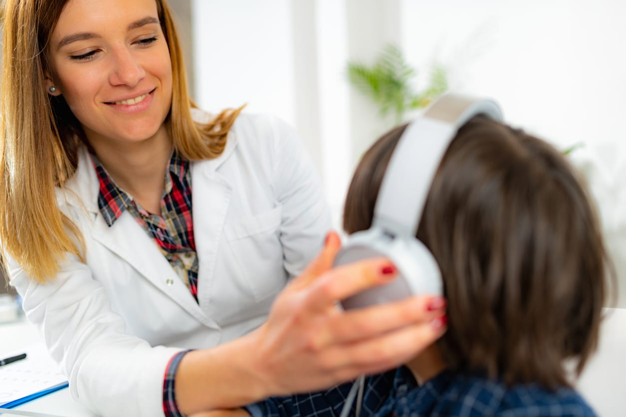 Audiologist putting headphones on a young boy.