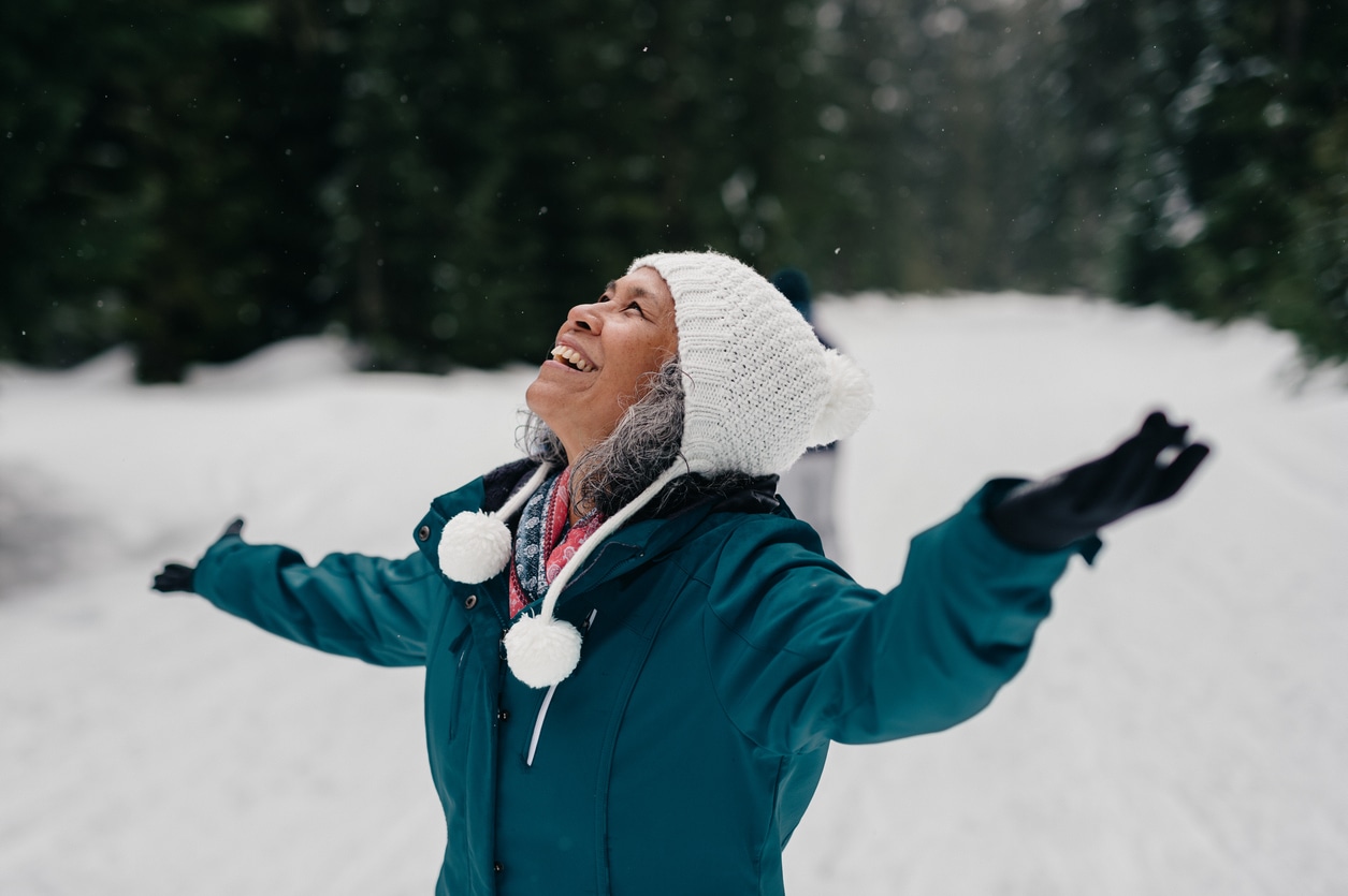 Senior woman enjoying the snowin the forest.