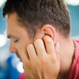 Man at the gym suffering from tinnitus after working out.
