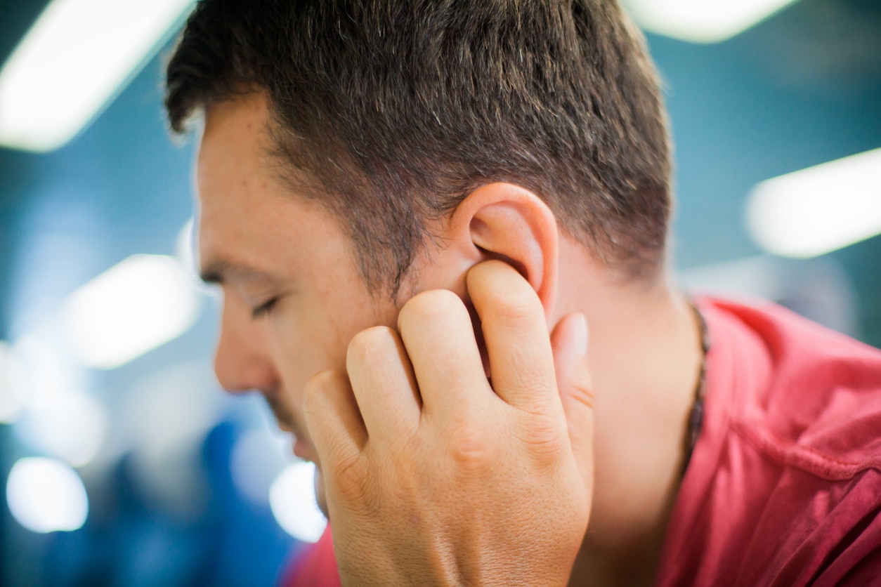 Man at the gym suffering from tinnitus after working out.